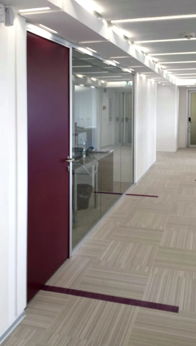 Corridoio con pareti vetrate e porta bordeaux