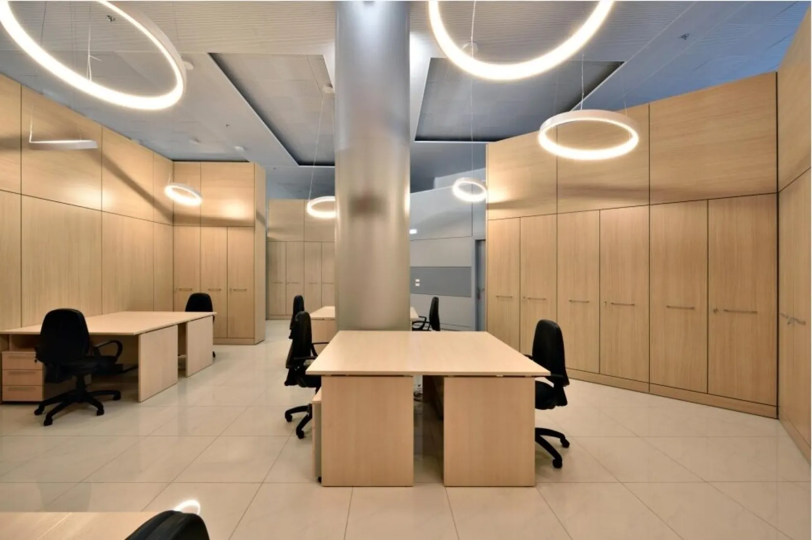 Open space con pareti attrezzate in legno e scrivanie