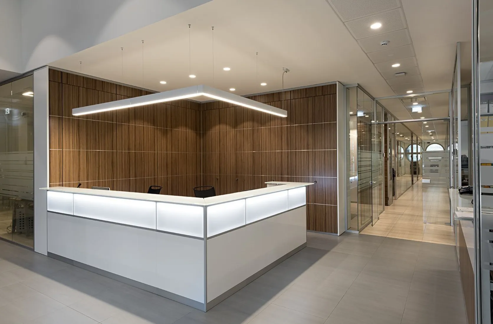 Reception con bancone luminoso e pareti in legno