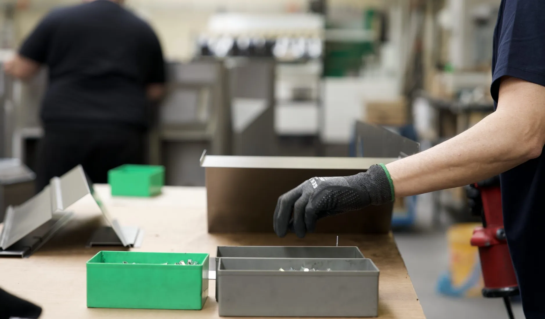 Operatore che prepara componenti metallici sul banco