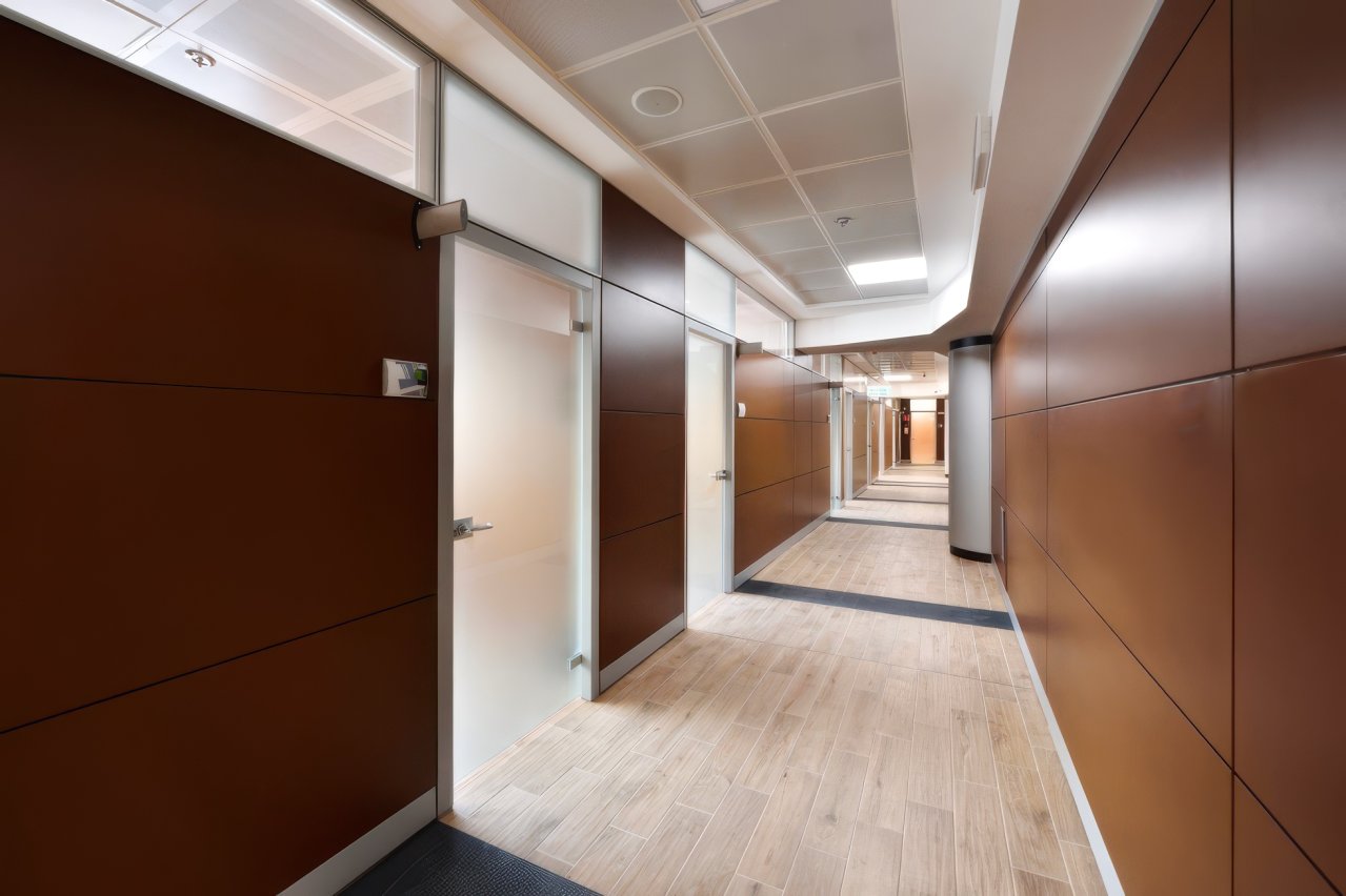 Corridoio di uffici con pareti divisorie in legno e porte in vetro satinato